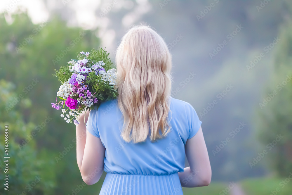 Beautiful young girl in blue dress holding the bouquet of wildflowers in her hands. Beautiful young girl in blue dress holding the bouquet of wildflowers in her hands.