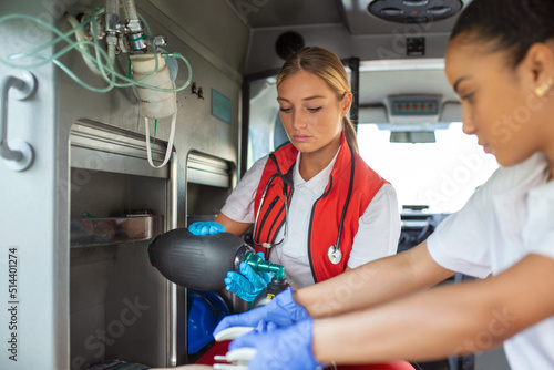 Paramedic using defibrillator (AED) in conducting a basic cardiopulmonary resuscitation. Emergency Care Assistant Putting Silicone Manual Resuscitators in an Ambulance. photo
