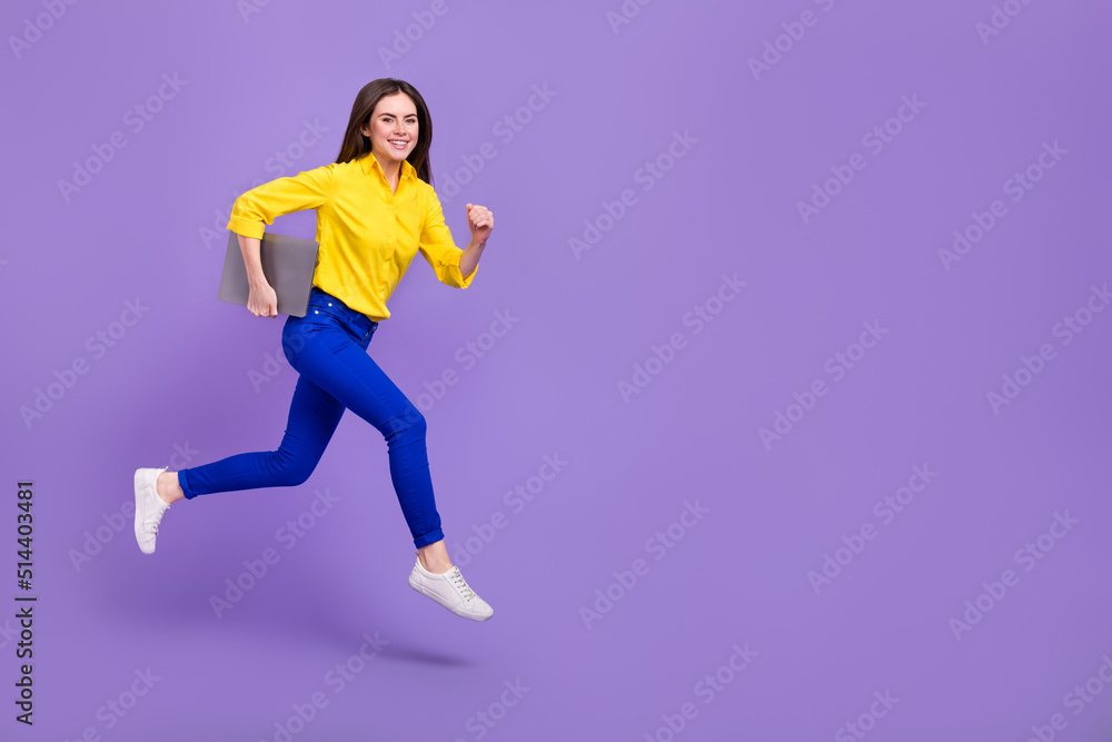 Full length body size view of attractive trendy energetic girl jumping holding laptop isolated over bright violet purple color background Full length body size view of attractive trendy energetic girl jumping holding laptop isolated over bright violet purple color background