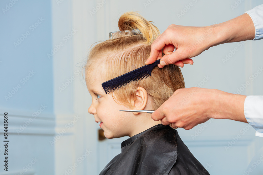 Fototapeta premium Profile of a little boy smiling while hairdresser do haircut