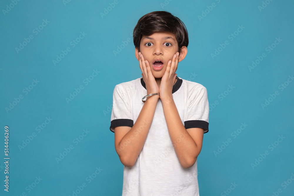 Portrait of shocked boy standing against blue background Portrait of shocked boy standing against blue background