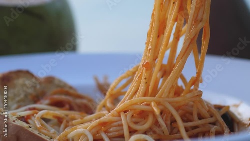 Man eats spaghetti in restaurant with a garlic bread