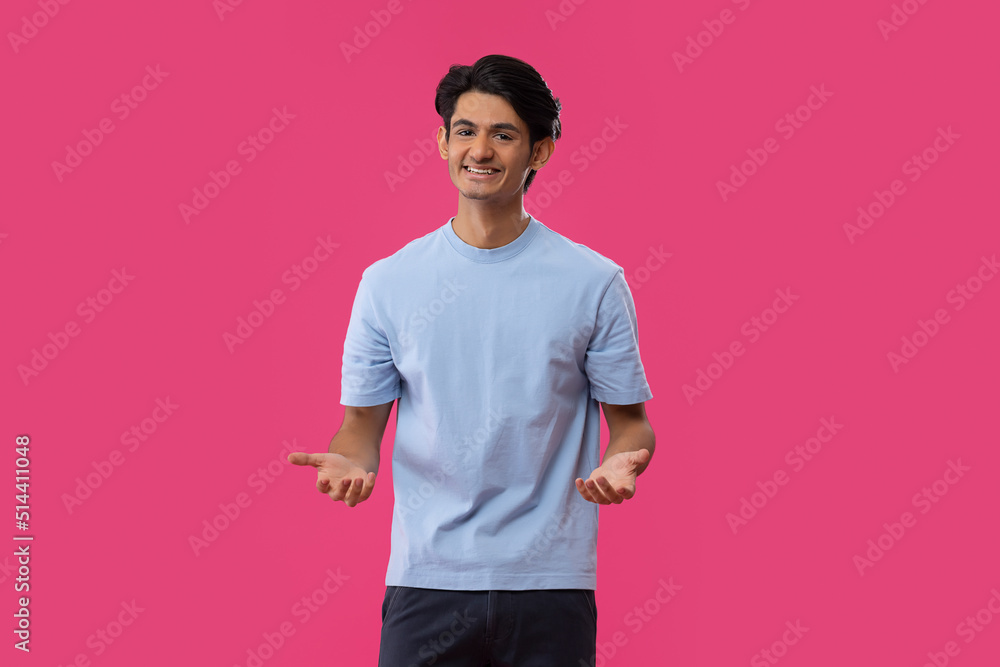 Portrait of smiling teenage boy gesturing while standing against pink background Portrait of smiling teenage boy gesturing while standing against pink background