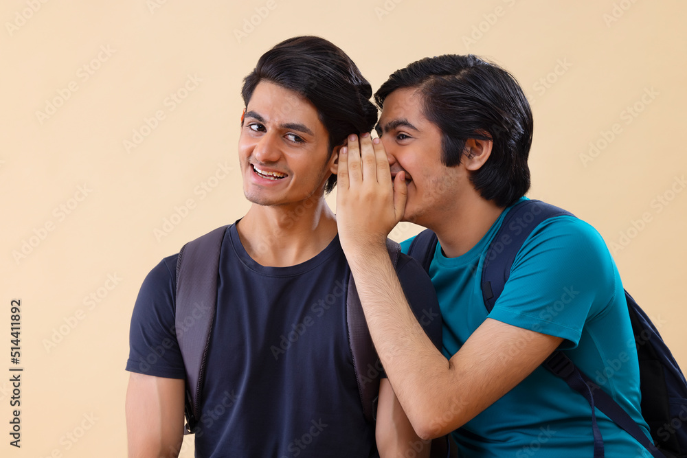 Naklejka premium Portrait of two teenage boys whispering to each other 