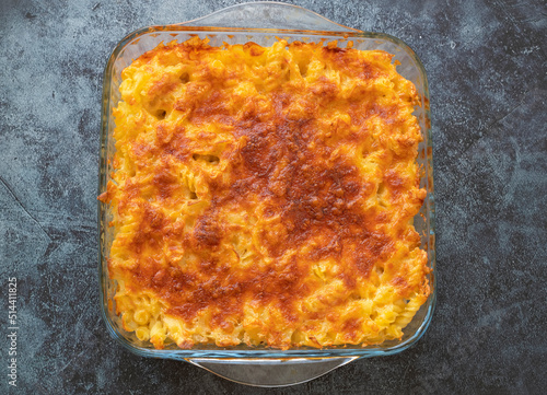 Pasta casserole bechamel sauce topped with melted mozzarella cheese and served in a white baking dish on a table (Turkish name; firinda makarna or firin makarna) photo