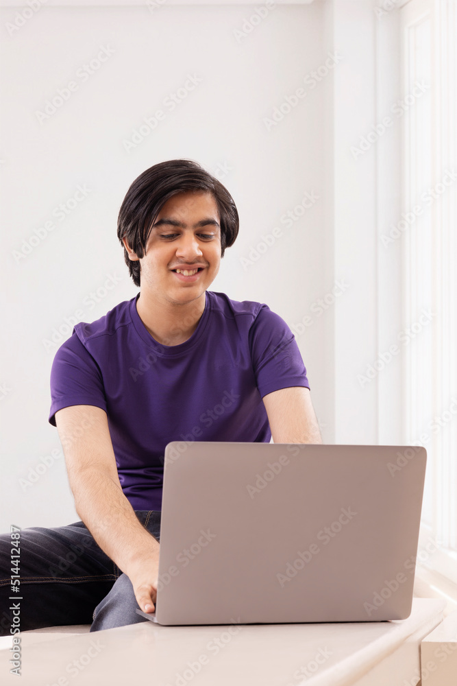 Portrait of teenage boy using laptop against plain background Portrait of teenage boy using laptop against plain background