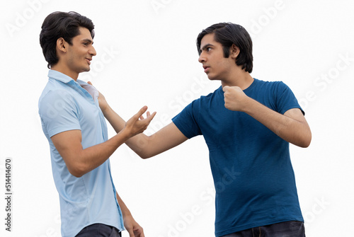 One teenage boy pulling the other by the collar of his shirt against white background