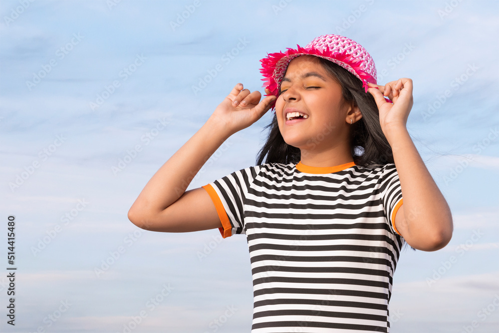 Portrait of little girl with hat against blue sky on a sunny day 