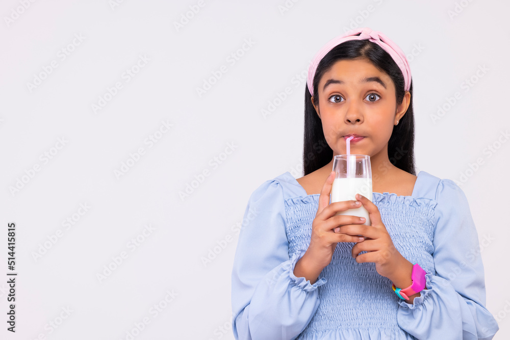 Portrait of a girl drinking milk against plain background Portrait of a girl drinking milk against plain background