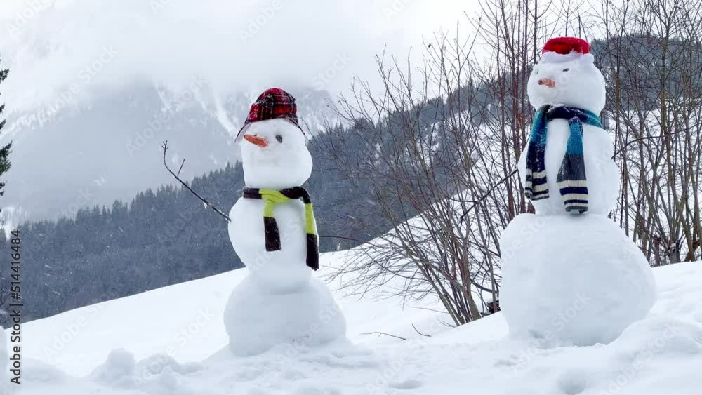 Two snowman with hat and scarf over Alps mountain and forest Two snowman with hat and scarf over Alps mountain and forest