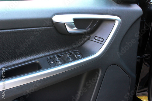 Door handle with windows controls and adjustments in black leather interior. Window switches.