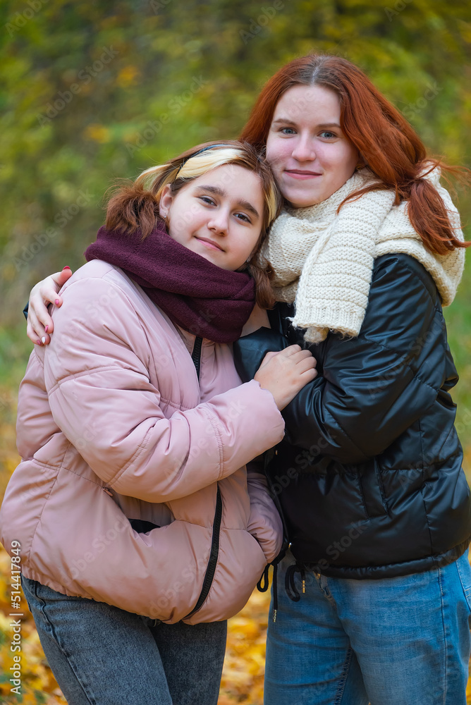 Fototapeta premium two red-haired smiling girls against the background of autumn nature, the concept of human emotions