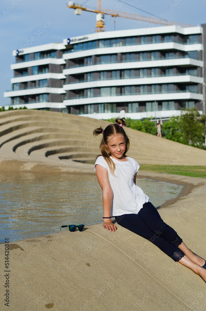 Fototapeta premium Happy family lifestyle and holiday concept. little girl walking, playing in fountain in city, street. laughing on a summer sunny day. Having fun. Staying cool