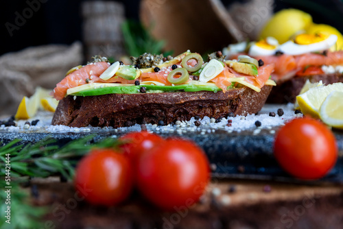 Salted salmon open sandwich with guacamole, avocado, olives, cheese, pesto and garlick. Healthy seafood