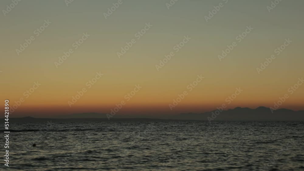 Time lapse of a sunset, sun goes behind the mountain. Small rocks in the foreground. Time lapse of a sunset, sun goes behind the mountain. Small rocks in the foreground.