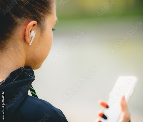 Young caucasian girl with wireless headphones in the park using tablet and smiling