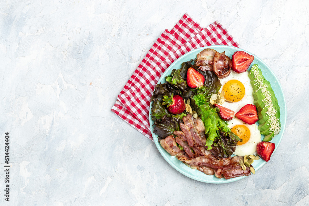 Plate with fried eggs, bacon, avocado, strawberries and fresh salad on a light background. Ketogenic diet food, healthy meal concept, Long banner format. top view Plate with fried eggs, bacon, avocado, strawberries and fresh salad on a light background. Ketogenic diet food, healthy meal concept, Long banner format. top view