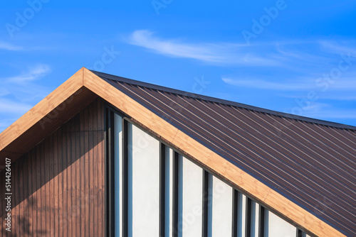 Wooden gable roof with battens decoration of vintage house against cloud on blue sky background