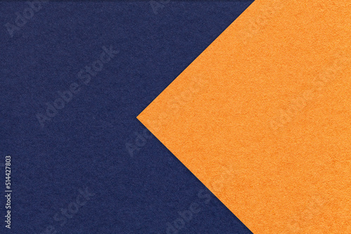 Texture of navy blue and orange paper background, half two colors with arrow, macro. Structure of dense craft cardboard