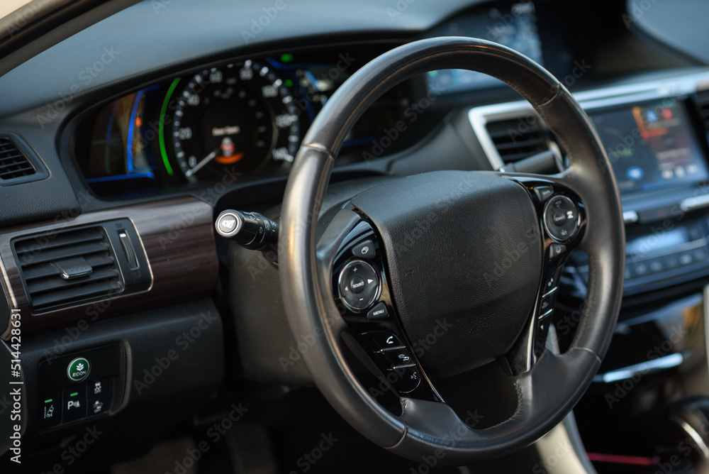 Black luxury modern car interior. Steering wheel, speedometer, display, and multimedia dashboard. Detail of car interior inside.