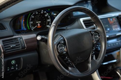 Black luxury modern car interior. Steering wheel, speedometer, display, and multimedia dashboard. Detail of car interior inside. © Serhii