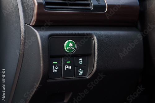 Green eco mode drive button in a modern car. Economic mode button, lane keep assist, parking assist, and electronic stability program (esp) button inside the car. Green ECON button on a dashboard. © Serhii