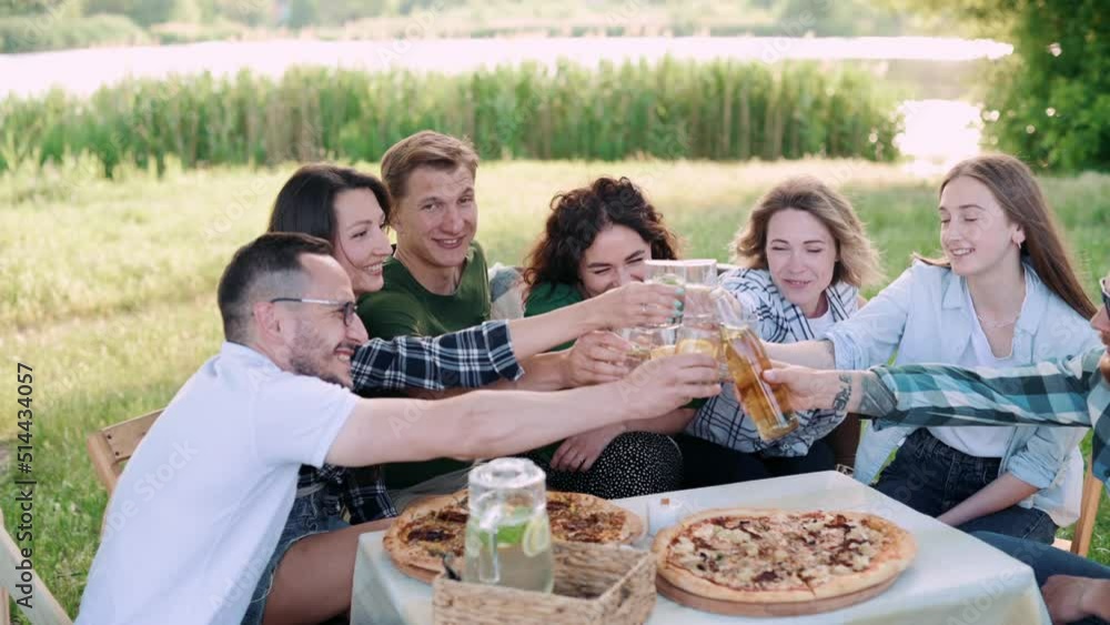 Group of friends are relaxing together outdoor. Young cheerful people clink glasses and laugh. Group of friends are relaxing together outdoor. Young cheerful people clink glasses and laugh.
