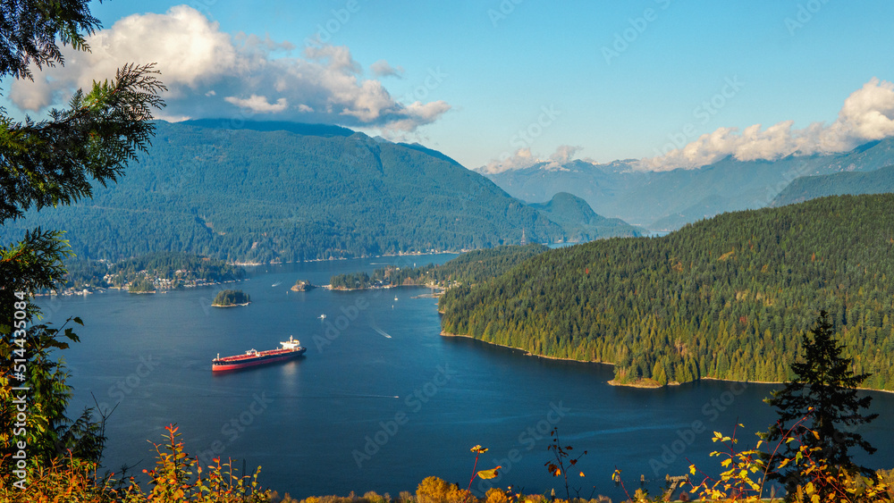 Clouds over North Shore mountains overlooking tranquil Burrard Inlet, BC, with oil tanker moored in foreground.