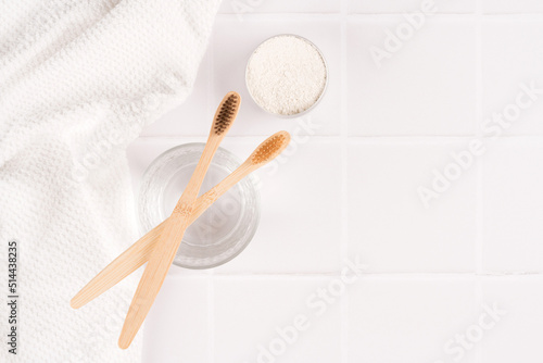 Top view on natural bamboo toothbrushes with mineral toothpowder kaolin in alu container at white table, copy space. Natural bath products, organic dentifrice