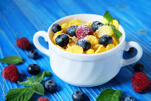 Healthy eating, food and diet concept - Cornflakes with berries and milk for breakfast.
