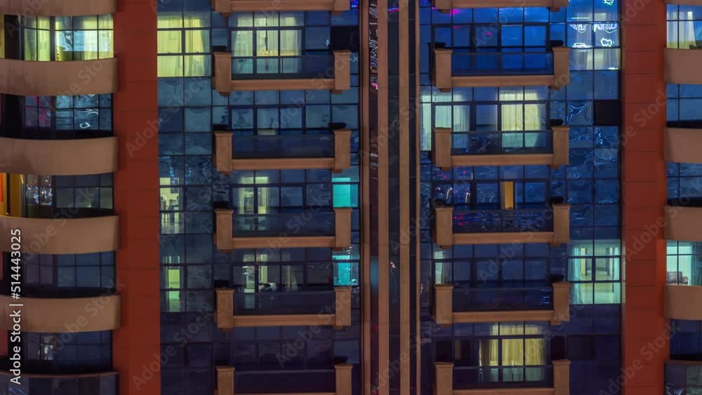 Night aerial view of apartment building glass window facade with illuminated lighted workspace rooms timelapse. Glowing light in skyscraper with glass surface Night aerial view of apartment building glass window facade with illuminated lighted workspace rooms timelapse. Glowing light in skyscraper with glass surface