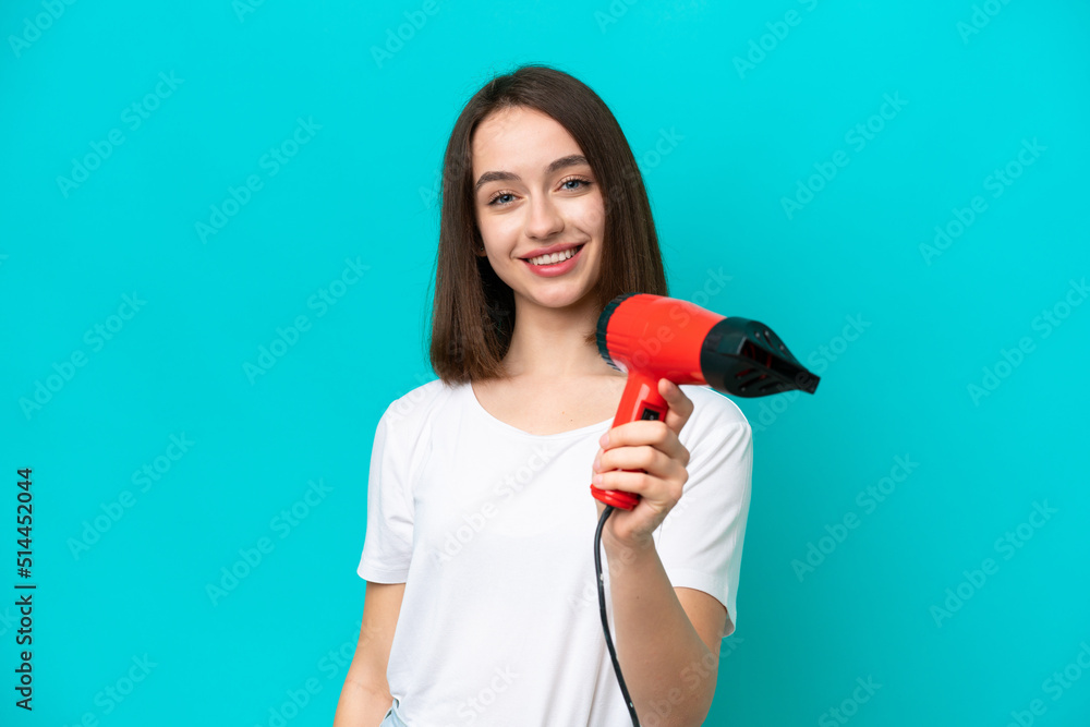 Young Ukrainian holding a hairdryer isolated on blue background with happy expression Young Ukrainian holding a hairdryer isolated on blue background with happy expression