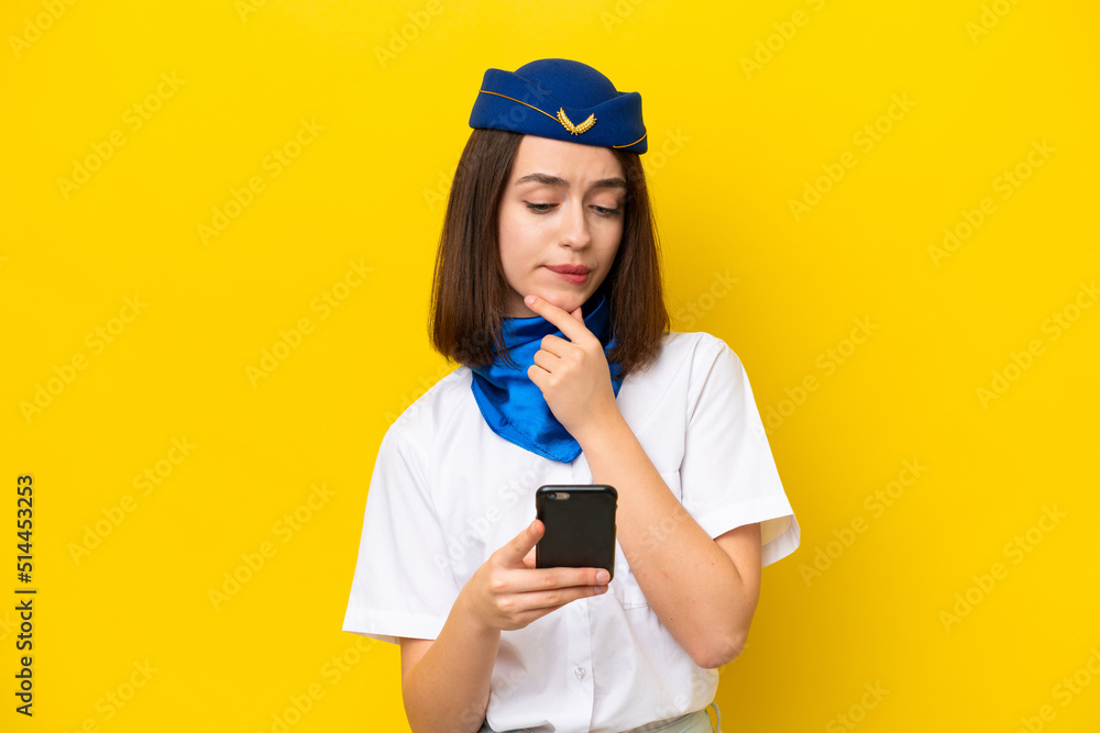 Airplane stewardess Ukrainian woman isolated on yellow background thinking and sending a message Airplane stewardess Ukrainian woman isolated on yellow background thinking and sending a message