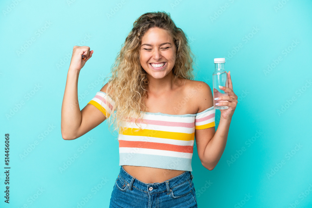 Young blonde woman with a bottle of water isolated on blue background doing strong gesture Young blonde woman with a bottle of water isolated on blue background doing strong gesture