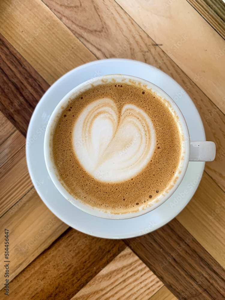 A cup of coffee latte On a wooden table. A mug of flat white coffee on a wooden background. Coffee art. Heart flower shape latte art. Copy space A cup of coffee latte On a wooden table. A mug of flat white coffee on a wooden background. Coffee art. Heart flower shape latte art. Copy space