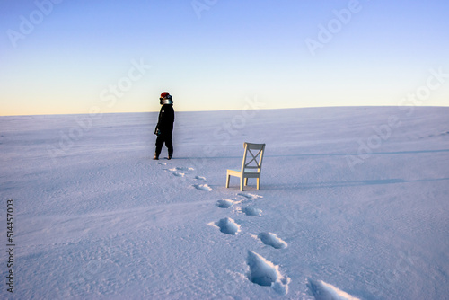 person walking on the snow field and white chair 