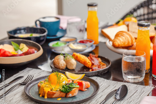 Delicious breakfast in luxury hotel. Table with plates full of various fresh food in cafe  freshly squeezed juices  eggs  fruits and sausages. Morning buffet food in front in modern resort.