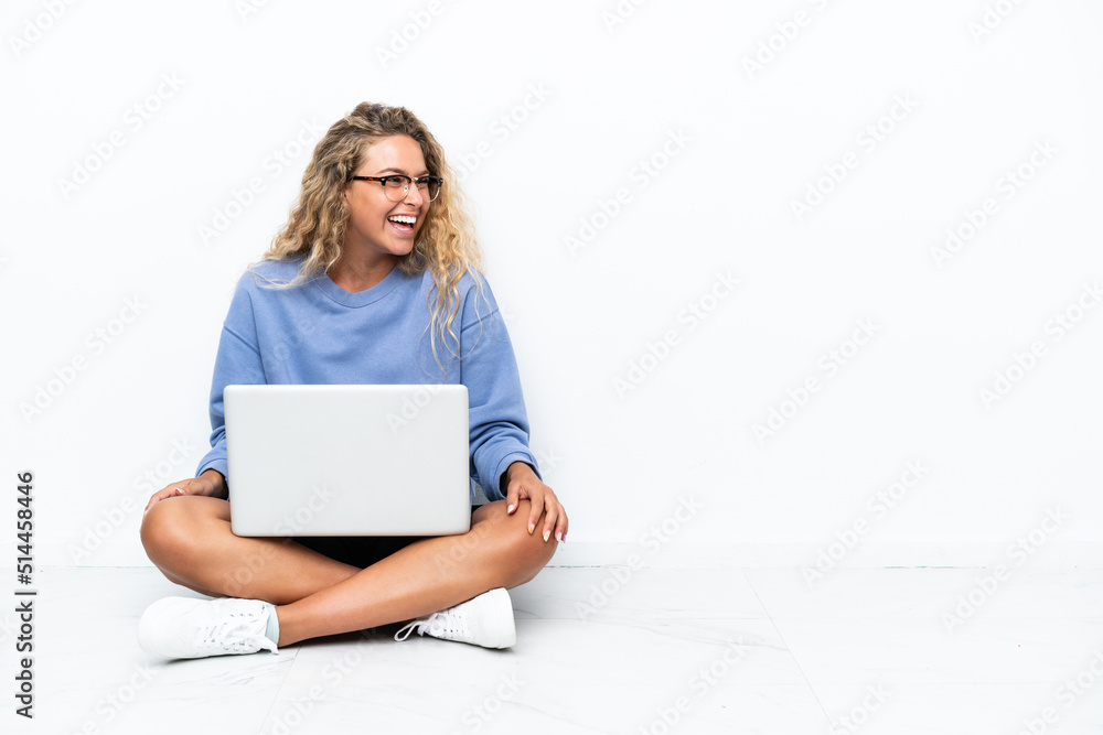 Girl with curly hair with a laptop sitting on the floor laughing in lateral position Girl with curly hair with a laptop sitting on the floor laughing in lateral position
