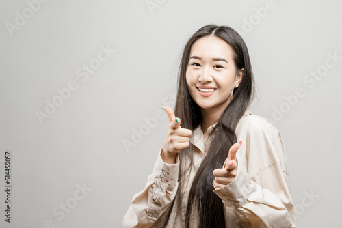 Portrait of a asian girl on a light background. a girl of Asian appearance points with her finger