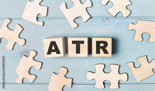 Blank puzzles and wooden cubes with the text ATR Average True Range lie on a light blue background.