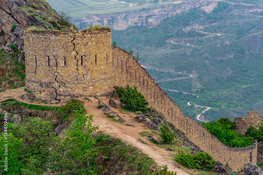 ancient tower and castle wall on top of a sheer cliff in a mountainous area, Shamil (Gunib) fortress in Dagestan,