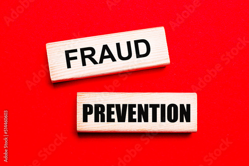 On a bright red background, there are two light wooden blocks with the text FRAUD PREVENTION