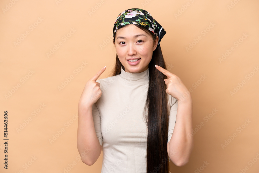 Young Chinese woman isolated on beige background giving a thumbs up gesture Young Chinese woman isolated on beige background giving a thumbs up gesture