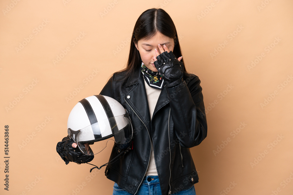 Young Chinese woman with a motorcycle helmet isolated on beige background with tired and sick expression