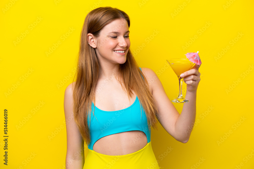 Young caucasian woman holding a cocktail isolated on yellow background with happy expression Young caucasian woman holding a cocktail isolated on yellow background with happy expression