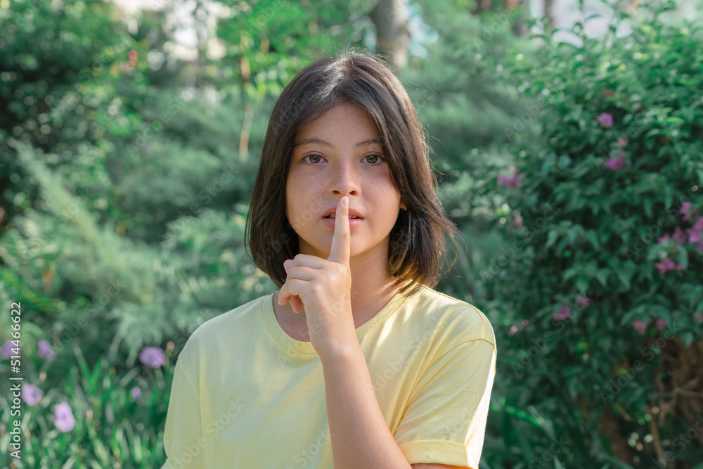A teenage girl raised her finger to her mouth. A teenage girl raised her finger to her mouth.