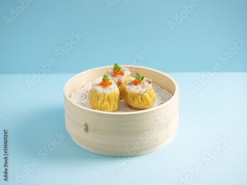 Steamed Pork Dumpling Siew Mai served in a wooden bowl with chopsticks isolated on mat side view on grey marble background photo