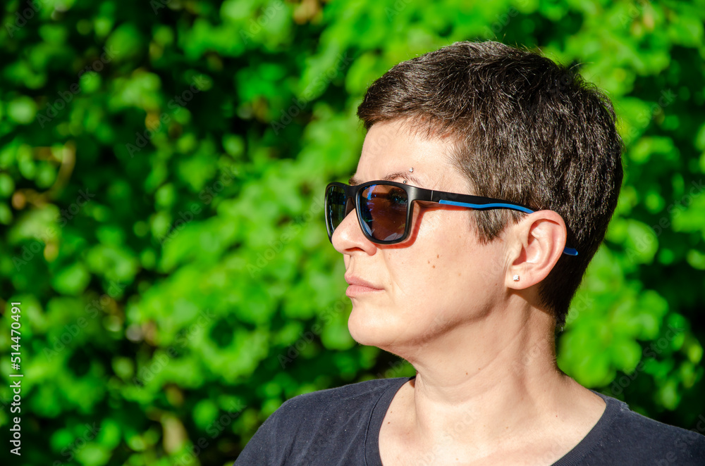 Portrait of a stylish young woman in profile on a summer day on a green natural background. Close-up of a woman's face with sunglasses. Space for text Portrait of a stylish young woman in profile on a summer day on a green natural background. Close-up of a woman's face with sunglasses. Space for text