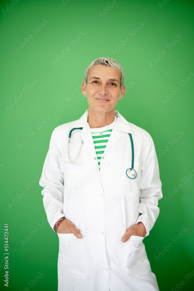 successful middle aged alternative woman doctor with short hair wearing white coat and stethoscope posing on green background successful middle aged alternative woman doctor with short hair wearing white coat and stethoscope posing on green background