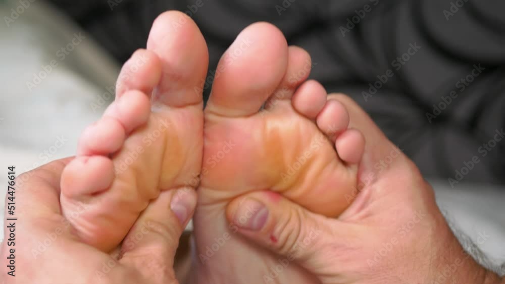 A man makes acupressure on the feet of a girl, close-up, selective focus A man makes acupressure on the feet of a girl, close-up, selective focus